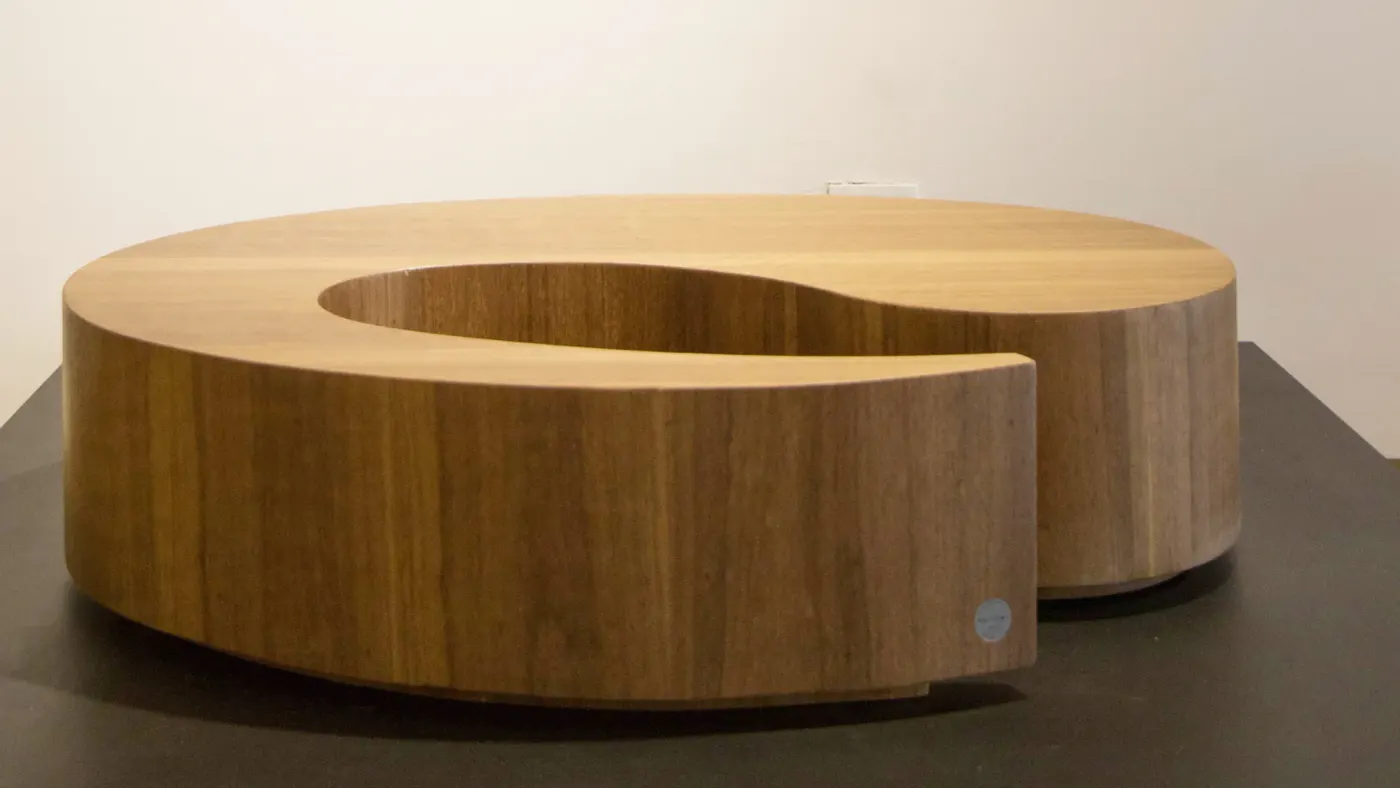 Mesa baixa de madeira formada por dois volumes curvos complementares